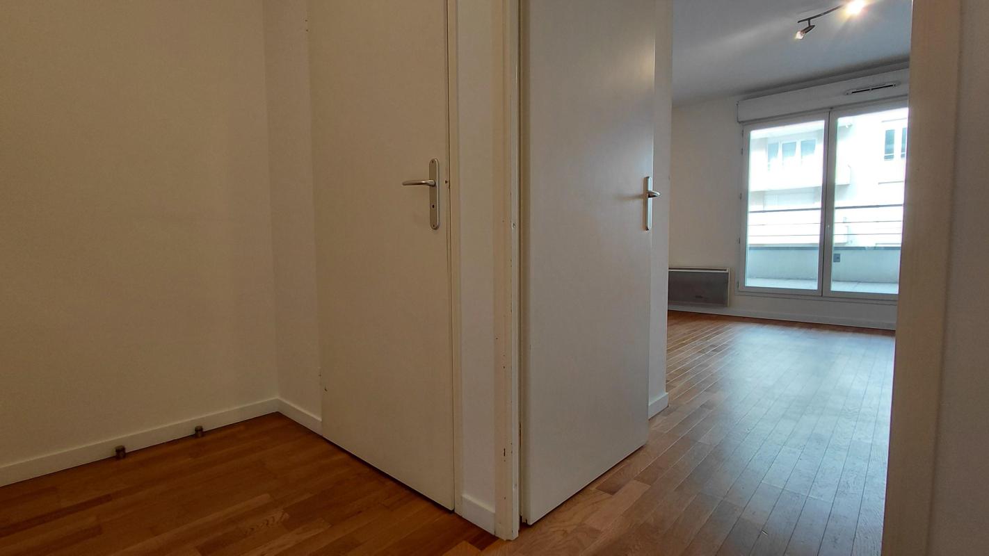 Photo 11 : petite entrée avec portes blanches, parquet, séjour clair au fond