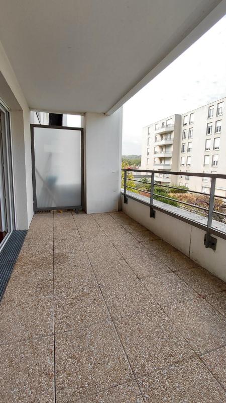 Photo 9 : terrasse longue vue sur immeuble voisin à plusieurs dizaines de mètres, arbres entre les deux, brise-vue en verre dépoli